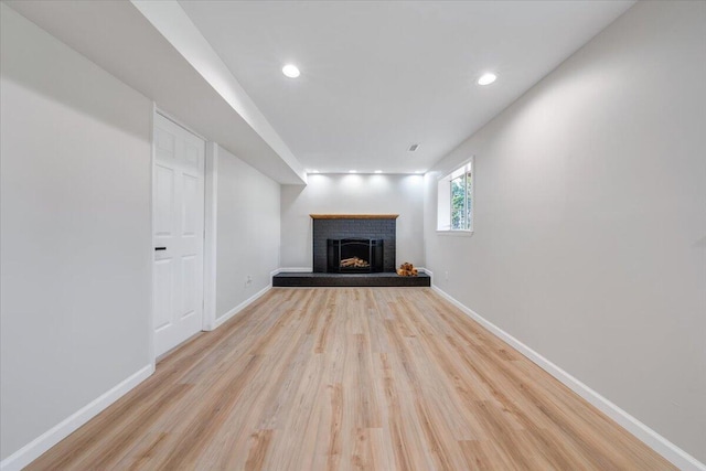 unfurnished living room with baseboards, a fireplace, recessed lighting, and wood finished floors