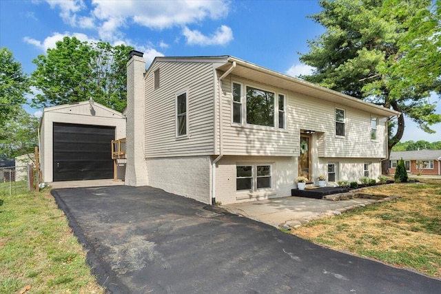 view of front of home with a detached garage, a chimney, an outdoor structure, and aphalt driveway
