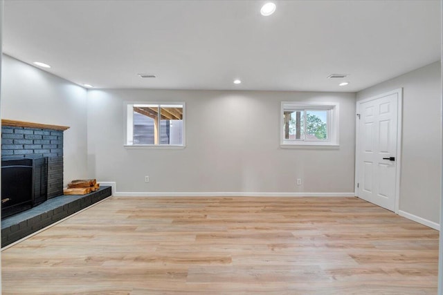 below grade area with a fireplace, light wood-style flooring, recessed lighting, baseboards, and visible vents