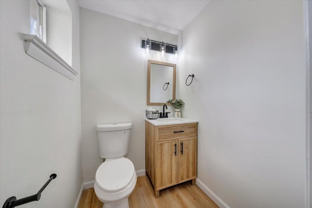 bathroom with vanity, baseboards, toilet, and wood finished floors