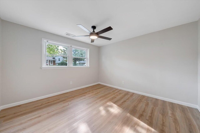 spare room with baseboards, a ceiling fan, visible vents, and light wood-type flooring