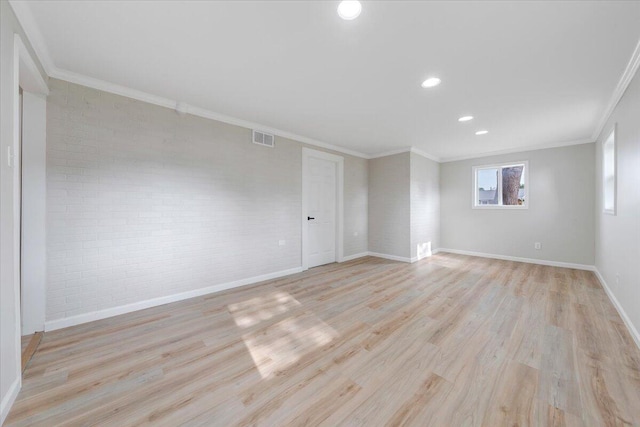 unfurnished room featuring brick wall, visible vents, crown molding, baseboards, and light wood-style floors