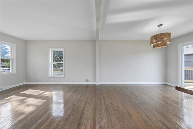 empty room featuring baseboards and dark wood-type flooring
