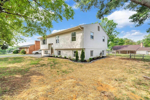 rear view of house featuring a yard and fence