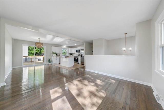 unfurnished living room with baseboards, visible vents, dark wood-type flooring, and a notable chandelier