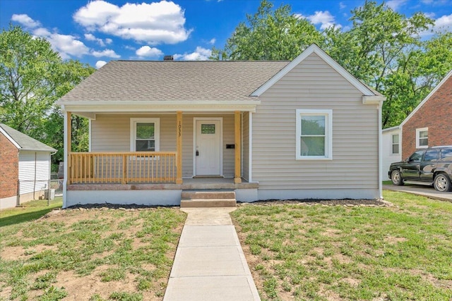 bungalow-style house with roof with shingles, covered porch, and a front yard