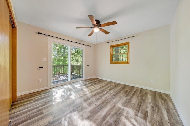 empty room with a ceiling fan, wood finished floors, and a wealth of natural light