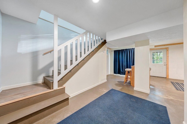 stairway featuring baseboards and finished concrete floors