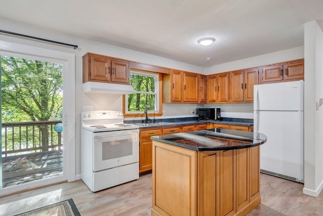 kitchen featuring dark countertops, light wood finished floors, under cabinet range hood, and white appliances