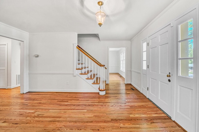 entrance foyer with crown molding, baseboards, stairs, and light wood-style floors