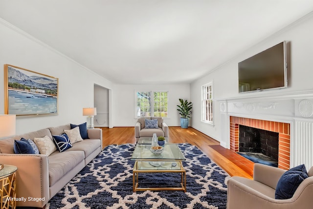 living room featuring crown molding, a brick fireplace, and wood finished floors
