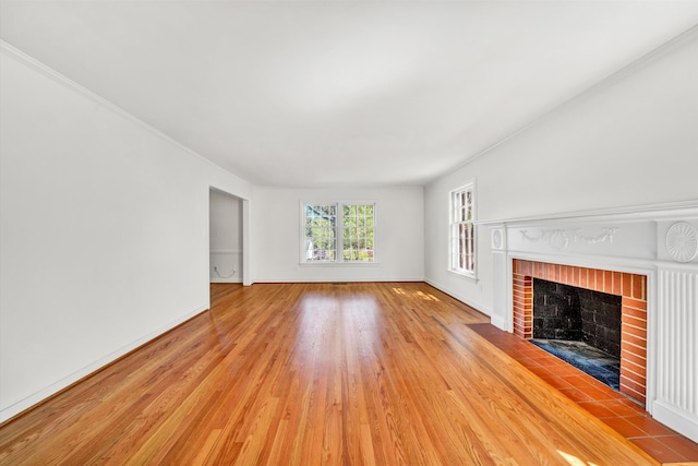 unfurnished living room with baseboards, a fireplace, and light wood-style flooring