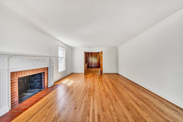 unfurnished living room with crown molding, baseboards, a fireplace, and wood finished floors