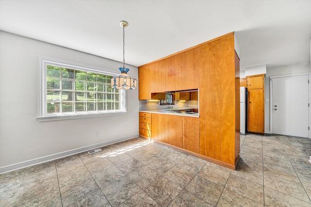 kitchen featuring baseboards, brown cabinetry, fridge, and visible vents
