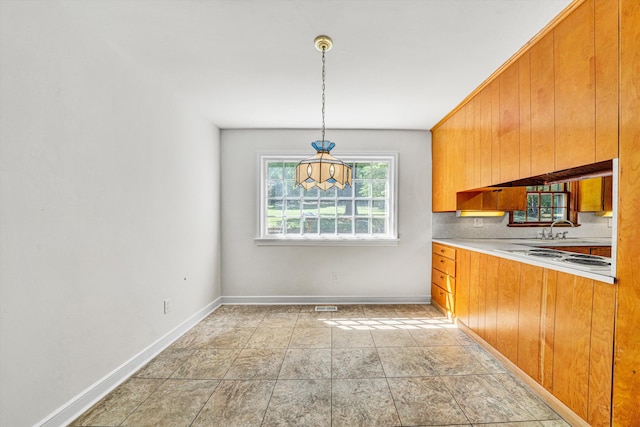 kitchen with light countertops, baseboards, brown cabinets, and white stovetop