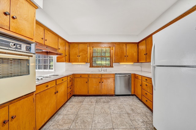 kitchen with light countertops, white appliances, a sink, and a wealth of natural light