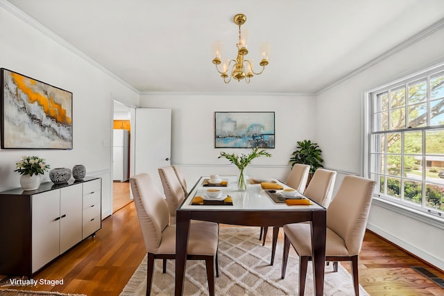 dining space featuring a healthy amount of sunlight, ornamental molding, and wood finished floors