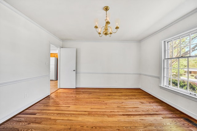 empty room featuring crown molding, an inviting chandelier, and a wealth of natural light