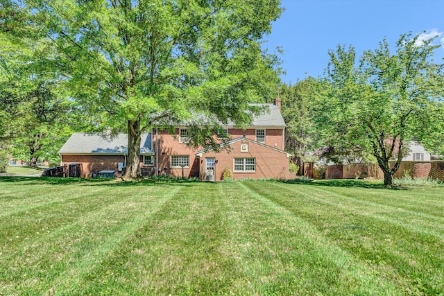 back of property with a yard, brick siding, and a chimney