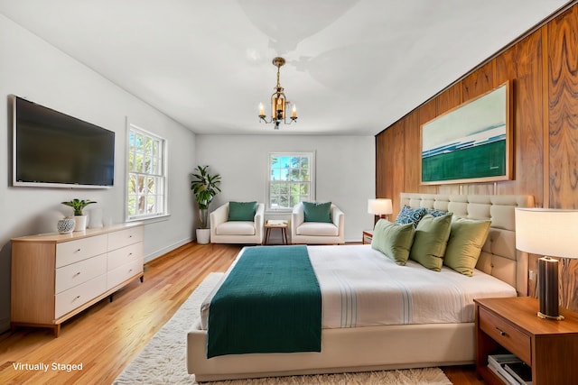bedroom with wooden walls, a chandelier, and light wood-type flooring