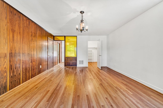 unfurnished room with baseboards, a chandelier, visible vents, and light wood-style floors