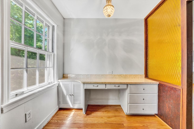 unfurnished office with baseboards, light wood finished floors, and built in study area