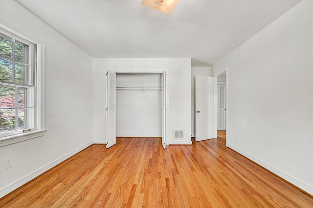 unfurnished bedroom with baseboards, multiple windows, light wood-style flooring, and visible vents