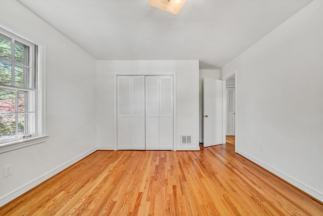 unfurnished bedroom with baseboards, multiple windows, light wood finished floors, and visible vents