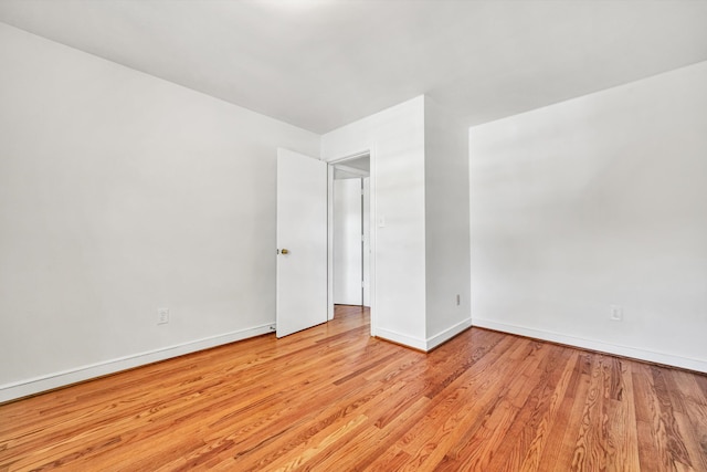 spare room featuring baseboards and light wood finished floors