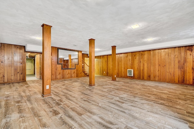 finished below grade area featuring wooden walls, stairway, wood finished floors, and visible vents
