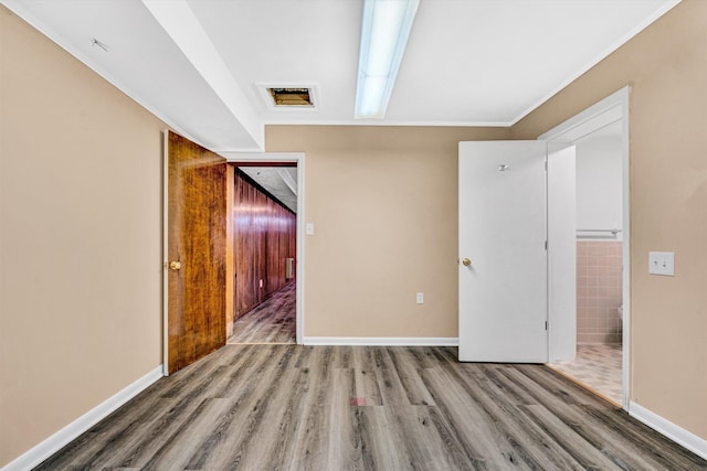 spare room featuring baseboards, crown molding, and wood finished floors