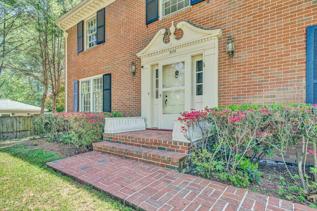 property entrance featuring fence and brick siding