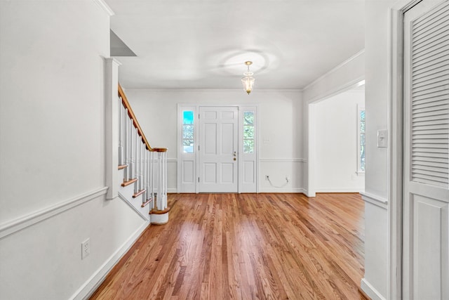 entrance foyer featuring light wood-style floors, baseboards, crown molding, and stairway