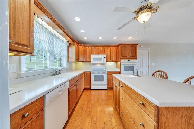 kitchen featuring a sink, light countertops, light wood-style floors, recessed lighting, and white appliances