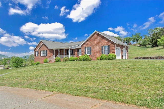 single story home with a garage, a front yard, a porch, and brick siding