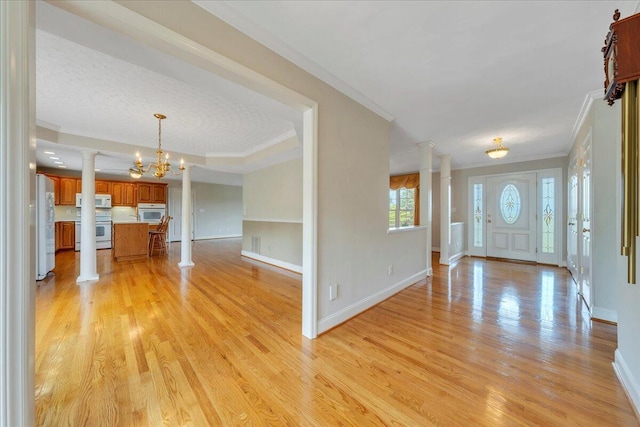 entrance foyer with ornamental molding, decorative columns, baseboards, light wood-style flooring, and a notable chandelier