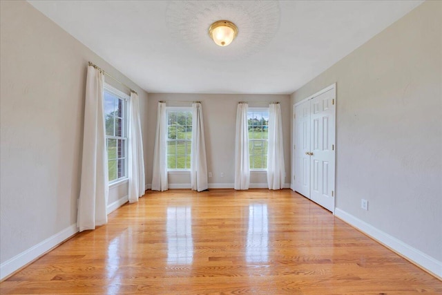 spare room with baseboards and light wood finished floors