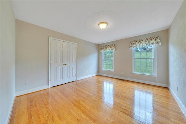 empty room featuring baseboards, wood finished floors, and visible vents