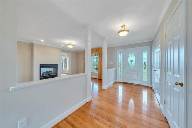 entryway with crown molding, baseboards, wood finished floors, and a fireplace