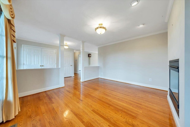 unfurnished living room featuring crown molding, baseboards, and light wood-type flooring
