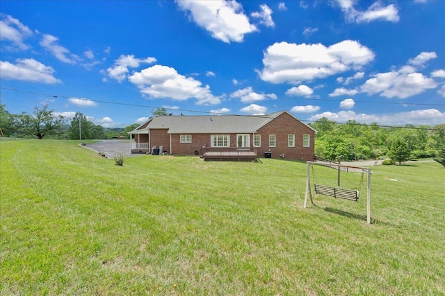 back of house with brick siding, a yard, and a deck