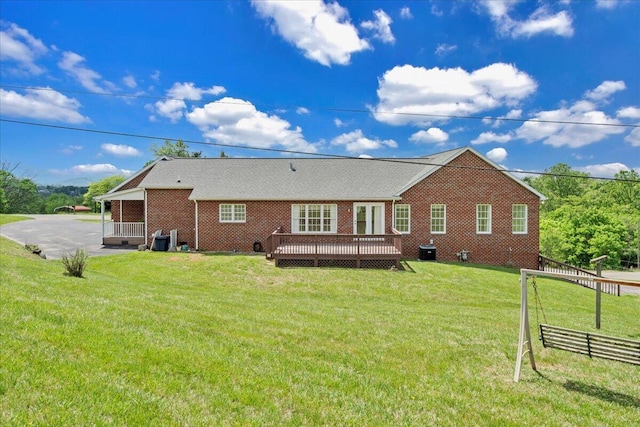 back of property with a wooden deck, fence, a patio, brick siding, and a lawn