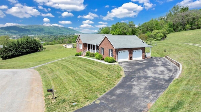 view of front of home with brick siding, a garage, a front yard, a mountain view, and driveway