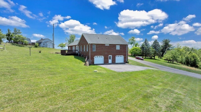 back of property featuring an attached garage, aphalt driveway, a yard, and brick siding