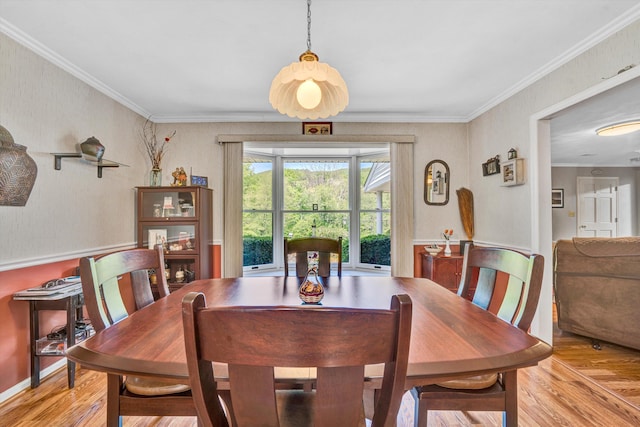 dining room with crown molding and light wood-style flooring