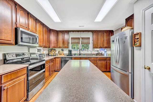 kitchen with a sink, stainless steel appliances, brown cabinets, and visible vents