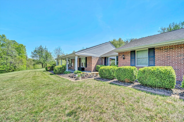 view of front of property with covered porch, brick siding, and a front yard