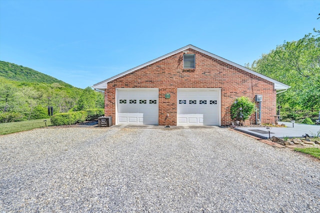 view of side of property featuring brick siding, a mountain view, and a garage