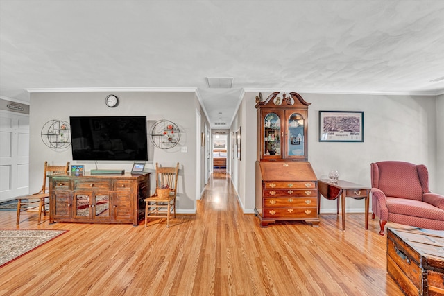 living area with crown molding, baseboards, visible vents, and wood finished floors