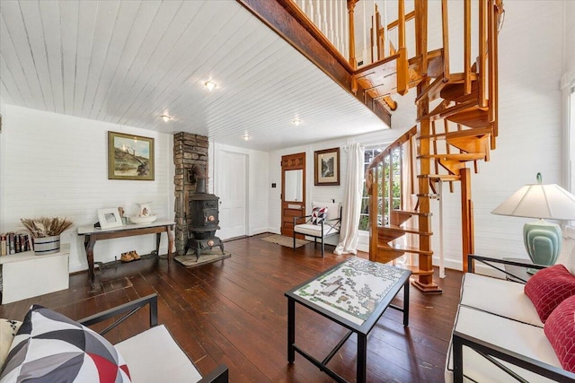 living area featuring stairs, wood-type flooring, and a wood stove
